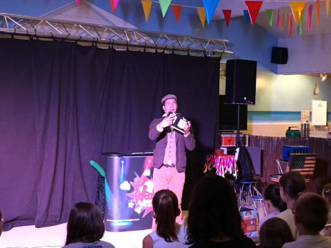 Mago si esibisce davanti a bambini sul palco al Flower Camping La Canadienne, Nouvelle-Aquitaine, Francia.