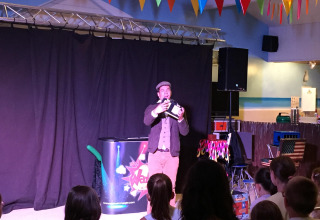 Mago si esibisce davanti a bambini sul palco al Flower Camping La Canadienne, Nouvelle-Aquitaine, Francia.