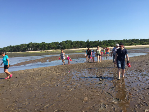 Des vacanciers traversent une plage boueuse au Flower Camping La Canadienne, Nouvelle-Aquitaine, France.