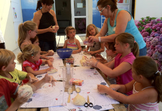 Bambini e adulti svolgono attività creative all’aperto al Flower Camping La Canadienne in Francia.