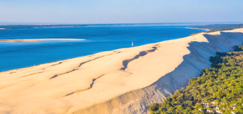 A breathtaking view of the Dune du Pilat near Arès, France, showing sandy dunes, forest, and the Atlantic coast.