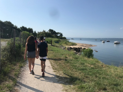 Mensen wandelen langs een pad bij het water in de buurt van Arès, Nouvelle-Aquitaine, Frankrijk, op een zonnige dag.