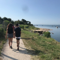 Mensen wandelen op een pad langs het water bij Arès, Nouvelle-Aquitaine, Frankrijk, op een zonnige dag.