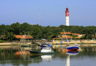 Kustzicht bij Arès in Nouvelle-Aquitaine, Frankrijk, met aangemeerde boten, huizen en een vuurtoren achteraan.