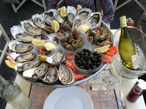 Bandeja de mariscos con ostras, camarones, caracoles, limón y vino blanco en un restaurante de Arès, Francia.