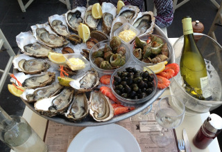 Plateau de fruits de mer avec huîtres, crevettes, bulots, citron et vin blanc au restaurant à Arès, France.