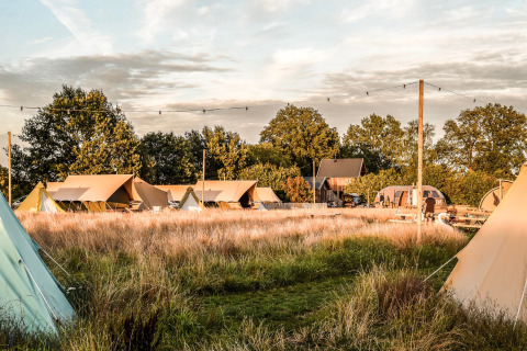 Vista de tiendas y campo en Holiday Park Mölke en Overijssel, Países Bajos, al atardecer.