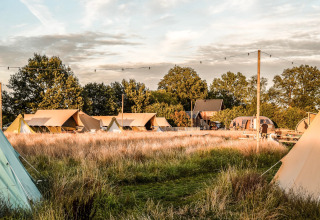 Vista de tiendas y campo en Holiday Park Mölke en Overijssel, Países Bajos, al atardecer.