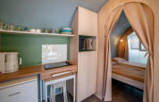 Innenansicht des Coco Suite Safari-Zelts im Sivinos Camping Boutique Italien mit Küchenecke und Bett.