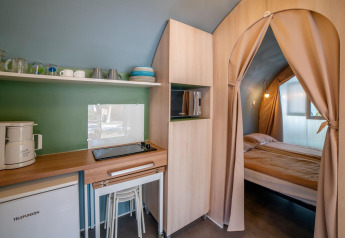 Binnenzicht van Coco Suite safaritent in Sivinos Camping Boutique in Italië met keuken en slaapkamer.