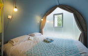 Schlafbereich im Coco Suite Safarizelt bei Sivinos Camping Boutique in Italien mit Bett und Fenster.