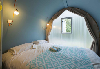 Slaapkamer in een Coco Suite safaritent bij Sivinos Camping Boutique in Italië, met bed en raam.