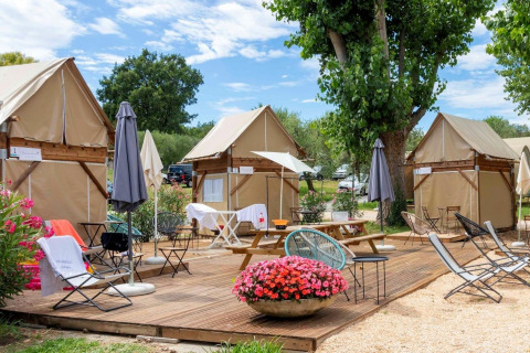 Buitenzitruimte met safaritenten, picknicktafels en bloemen bij Sivinos Camping Boutique, Italië.