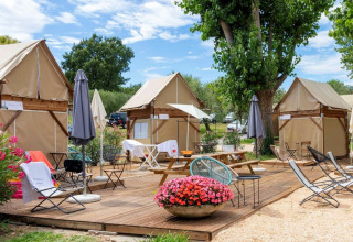 Buitenzitruimte met safaritenten, picknicktafels en bloemen bij Sivinos Camping Boutique, Italië.