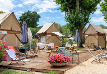 Zona de estar al aire libre y tiendas safari con mesas de picnic en Sivinos Camping Boutique, Italia.