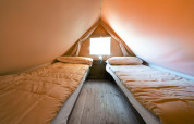 Zwei Einzelbetten in einem komfortablen Glamping-Zelt mit Holzfußboden und Fenster für naturnahes Übernachten.