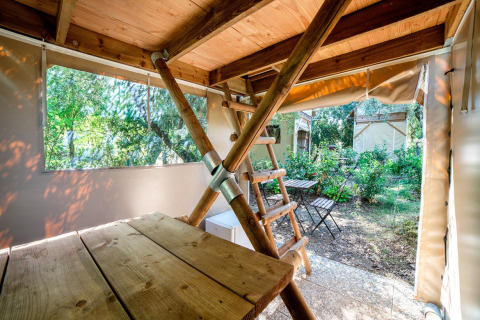 Binnenzicht in safaritent Airstay bij Sivinos Camping Boutique Italië, met houten tafel en uitzicht op tuin.