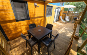 Houten terras bij Tiny House Sivinos Camping Boutique in Italië met eettafel en loungestoelen.