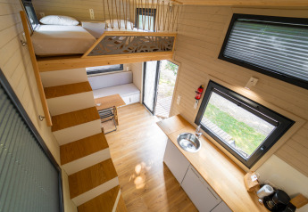 Moderne tiny house met vide, keuken, trap en zithoek bij Sivinos Camping Boutique, Italië.