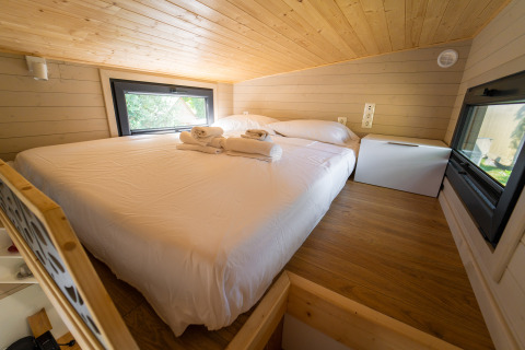 Slaapkamer in een tiny house bij Sivinos Camping Boutique in Italië, met gezellige sfeer en grote ramen.