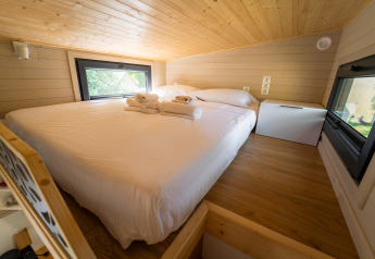 Slaapkamer in een tiny house bij Sivinos Camping Boutique, Italië, met knusse inrichting en grote ramen.
