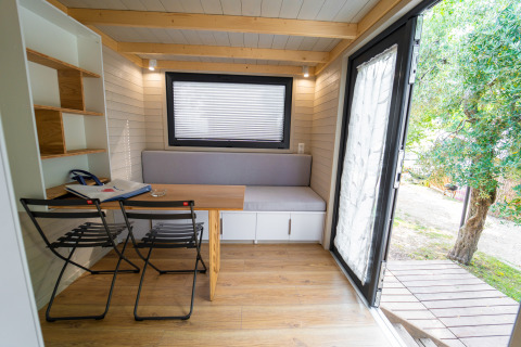 Gezellig en compact interieur van een tiny house bij Sivinos Camping Boutique in Italië, met open deur naar buiten.