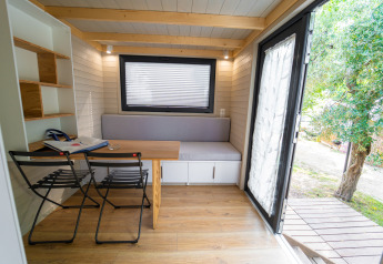 Licht en compact interieur van een tiny house bij Sivinos Camping Boutique in Italië, met open deur naar buiten.