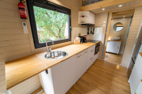 Compacte moderne keuken in een tiny house bij Sivinos Camping Boutique in Italië, met houten werkblad.