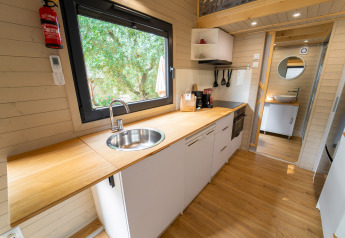 Moderne compacte keuken in een tiny house bij Sivinos Camping Boutique in Italië, met houten aanrechtblad.