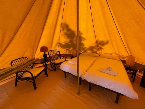Interior de la tienda Bell Tent en Sivinos Camping Boutique, Italia, con cama doble y zona de asientos.