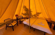 Intérieur de la tente Bell Tent au Sivinos Camping Boutique, Italie, avec lit double et coin salon.