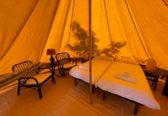 Indretning af Bell Tent på Sivinos Camping Boutique i Italien med dobbeltseng og komfortable møbler.