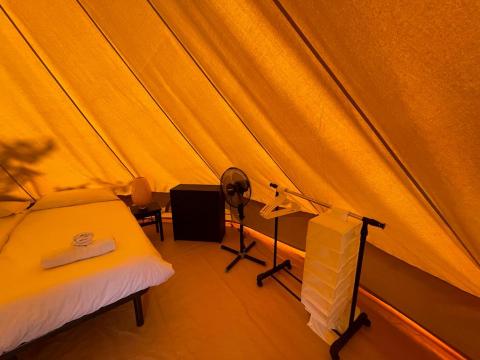Vue intérieure de la Bell Tent au Sivinos Camping Boutique en Italie avec lit, chaise et ventilateur.