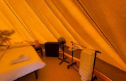 Vue intérieure de la Bell Tent au Sivinos Camping Boutique en Italie avec lit, chaise et ventilateur.