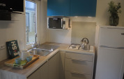 Angolo cottura moderno per glamping con lavello, fornello a gas, frigo, microonde e pensili blu.