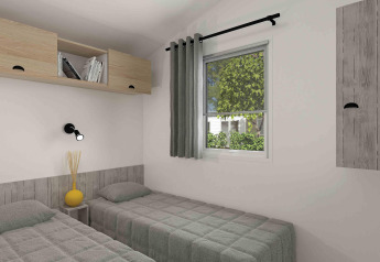 Modern glamping room with two single beds, a window with a green view, and minimal wooden storage units.