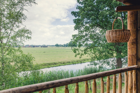 Vista da un balcone con cestino, fiume e alberi al parco vacanze Mölke, Overijssel, Paesi Bassi.