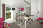 Interno di casa mobile moderna con cucina, tavolo da pranzo, cuscini colorati e vista sul giardino.