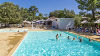 Udendørs swimmingpool med gæster, liggestole og parasoller på Flower Camping Monplaisir i Nouvelle-Aquitaine.