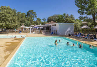 Außenpool mit Gästen, Liegestühlen und Sonnenschirmen auf dem Flower Camping Monplaisir in Nouvelle-Aquitaine.