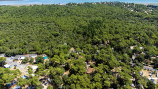 Luchtfoto van Flower Camping Monplaisir in Nouvelle-Aquitaine, Frankrijk, omringd door bos en nabij de zee.