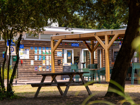 Receptie en buitenterras met picknicktafels bij Flower Camping Monplaisir in Nouvelle-Aquitaine, Frankrijk.