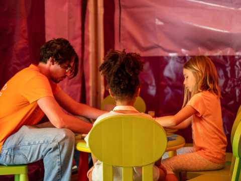 Un homme et deux enfants font des activités ensemble à une petite table au Flower Camping Monplaisir, France.