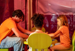 Een man en twee kinderen zijn samen bezig aan een tafeltje op Flower Camping Monplaisir, Frankrijk.