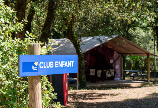 Blue 'CLUB ENFANT' sign in front of kids club tent at Flower Camping Monplaisir, Nouvelle-Aquitaine, France.