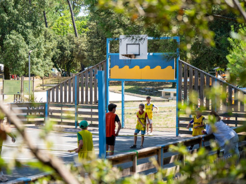 Kinder spielen Basketball auf einem Außenplatz im Flower Camping Monplaisir, Nouvelle-Aquitaine, Frankreich.