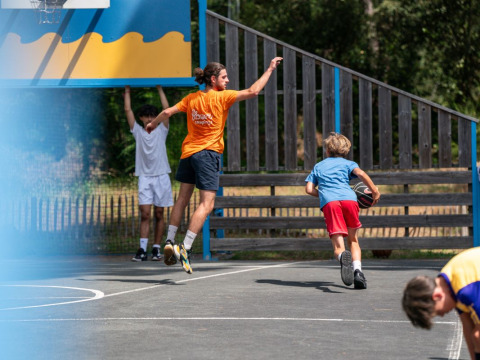 Kinderen en volwassenen spelen basketbal op het terrein van Flower Camping Monplaisir in Nouvelle-Aquitaine.