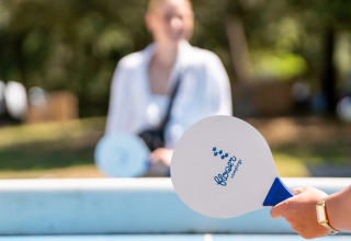Twee mensen spelen tafeltennis met Flower Camping Monplaisir batjes op een vakantiepark in Frankrijk.