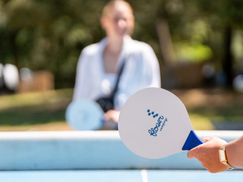Two people playing table tennis outside with Flower Camping Monplaisir paddles at a holiday park in France.