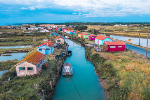 Casette colorate e barche lungo un canale al Flower Camping Monplaisir in Nouvelle-Aquitaine, Francia.